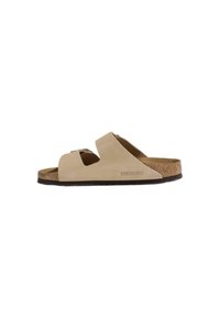 Sandales Birkenstock beige clair avec une semelle en liège, deux larges brides et un matériau doux ressemblant à du daim. Semelle extérieure en caoutchouc texturé.