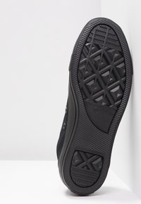 Černé tenisky s texturovanou gumovou podešví s geometrickým vzorem a hladkým semišovým svrškem. Kovové očka a kulat�é tkaničky dotvářejí design.