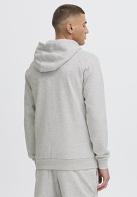 Grå hettegenser laget av bomullsblanding; har snor i hette, ribbestrikkede manchetter og midjebånd. Glatt tekstur med et enkelt design.