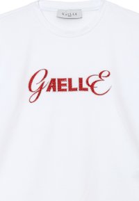 T-shirt bianco in cotone con lettering in strass rossi che scrivono "Gaëlle" sulla parte anteriore. Design classico a girocollo con maniche corte.