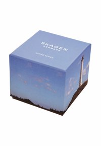 Fyrkantig förpackning med en scenisk avbildning av ett fyrtorn och himmel, främst i nyanser av blått, med vit varumärkestext ovanpå.