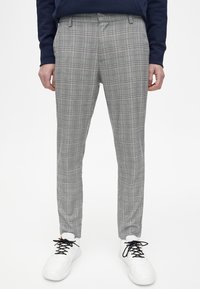 Grå ruta byxor med en smal passform, med ett rutmönster och en subtil textur, kombinerade med vita sneakers.