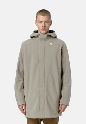 Cappotto impermeabile beige chiaro con colletto alto, cappuccio e logo argentato. Presenta un design slanciato e maniche lunghe. Texture liscia.