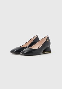 Black leather pumps with a pointed toe and a low block heel. Gold accent at the base of the heel. Smooth texture. Classic design.
