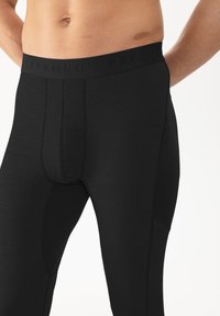 Schwarze Sportleggings mit glatter Textur, ausgestattet mit einem breiten elastischen Bund und dezenten Nähten für eine figurbetonte Passform.