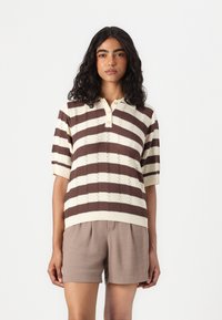 Brun og kremstripet kortermet polo genser med et teksturert mønster og knappekrage, kombinert med brune shorts.