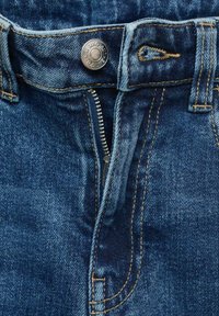 Modre kavbojke imajo zadrgo, kovinsko gumbno zapiranje in kontrastno rumeno šivanje ob pasu in žepih.