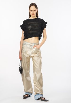 Maglione corto a maglia aperta nero con maniche a volant, abbinato a pantaloni larghi metallici oro e scarpe nere con punta. Piccola borsa nera.