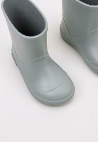 Botas de lluvia de goma gris claro con una textura suave, punta redondeada y un forro interno suave, que cuentan con un diseño bajo en el tobillo y suelas texturizadas.