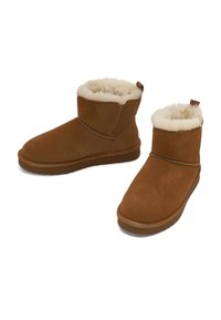 Braune Wildleder-Ankle Boots mit weicher cremefarbener Fütterung, runder Zehenform und flacher Gummisohle. Verfügt über eine Zuglasche für einfaches Anziehen.
