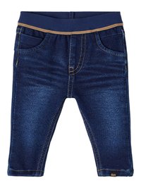 Vaqueros de mezclilla con un lavado oscuro, cintura elástica en color azul marino con costuras beige, diseño de cinco bolsillos y detalles de costura visibles.