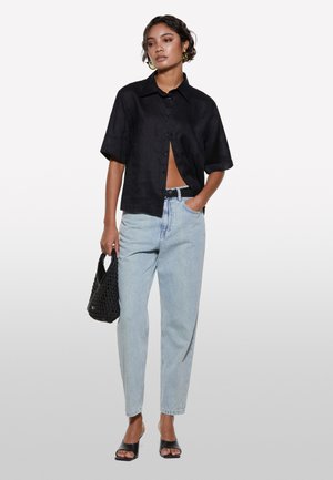 Schwarzes kurzärmeliges Button-up-Hemd, hellblaue hochgeschnittene Jeans, schwarze geflochtene Handtasche und schwarze offene Absatzschuhe. Glatte Texturen, lockerer Schnitt.