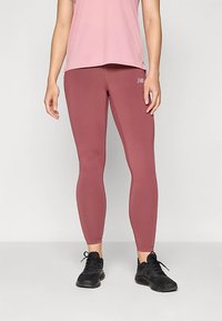 Bordowe legginsy z elastycznego materiału, dopasowany krój i gładka faktura. Połączone z różową bluzką i czarnymi trampkami.