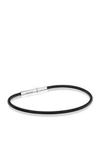 Collar negro enrollado con un cierre magnético cilíndrico de acero inoxidable sobre una superficie blanca reflectante.