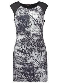 Robe sans manches longueur genou avec des manches courtes noires et un motif texturé abstrait noir et blanc sur le corps.