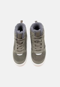 Ζευγάρι γκρίζων ψηλών αθλητικών παπουτσιών με ψεύτικη γούνα, κούμπωμα με κορδόνια και λευκές καουτσούκ σόλες, προσανατολισμένο από πάνω σε λευκό φόντο.