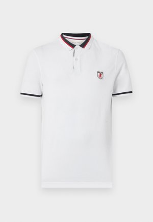 Bela polo majica s kratkimi rokavi, s črnim in rdečim robom na ovratniku in rokavih, dvema gumboma na sprednji strani ter majhno logotipno značko na levi strani prsnega koša.