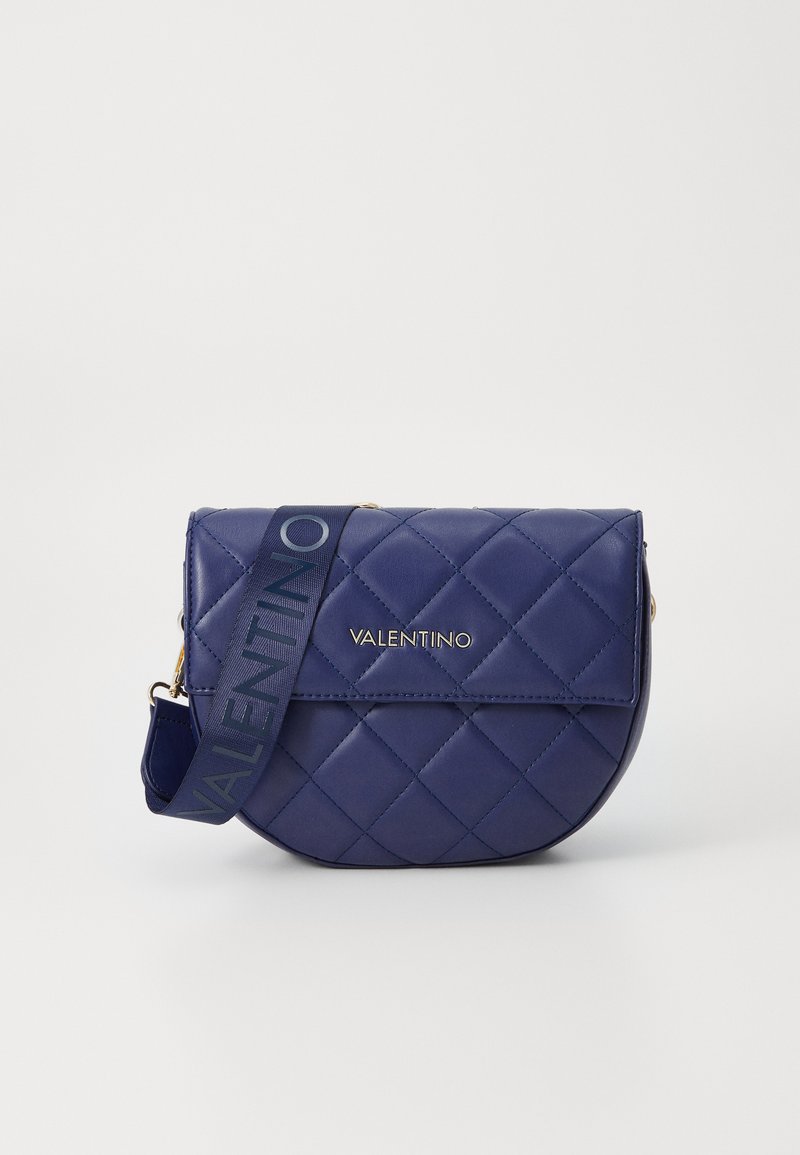 Geantă crossbody din piele bleumarin matlasată, cu o formă rotunjită, accesorii aurii și o curea din materiale cu marcajul "VALENTINO" în albastru.