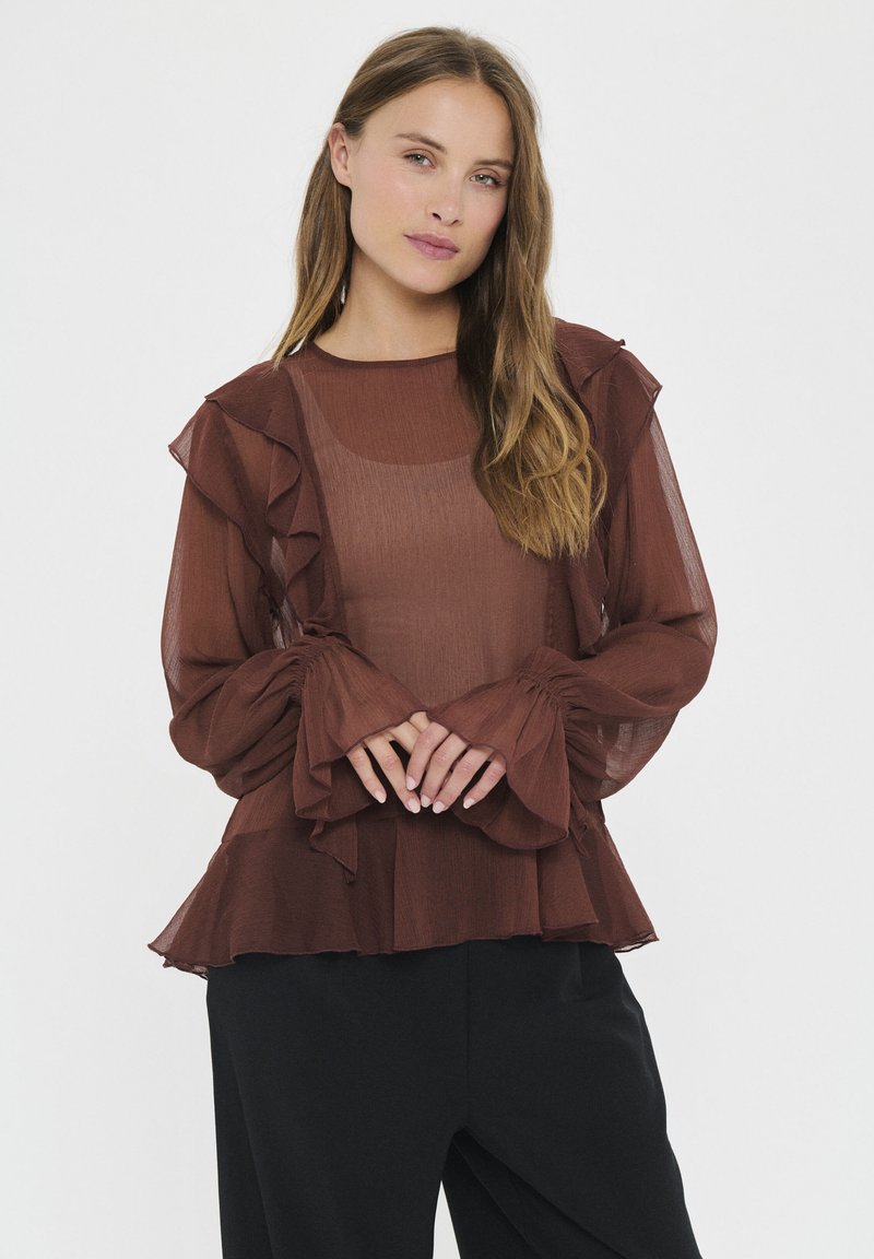 Blusa marrón transparente con acentos con volantes a lo largo del escote y las mangas, que presenta mangas largas y fluidas, además de un dobladillo acampanado.