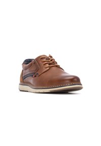 Zapato de cuero marrón con un acabado suave, diseño de cordones, franja en contraste de color marino y una suela de goma beige con un patrón de banda de rodadura visible.