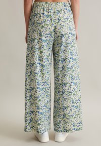 Wide-leg trousers made of lightweight fabric. Floral pattern with blue and green flowers on a light background. Elastic waistband.