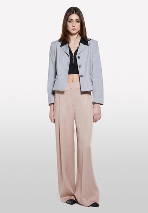 Gray cropped blazer with black collar and three buttons, paired with loose-fitting light pink trousers and black pointed shoes.