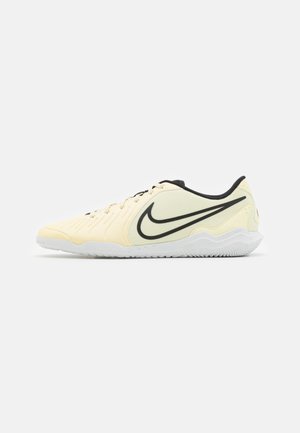 Vue latérale de baskets Nike en jaune clair avec des accents noirs, présentant une tige texturée et une semelle en caoutchouc blanche avec un motif ondulé.