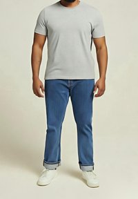 Šedé tričko s krátkými rukávy, modré džíny s ohrnutými nohavicemi a bílé tenisky. Jednoduchý, neformální střih s klasickým kulatým výstřihem.