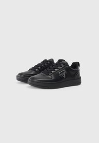 Zapatillas de cuero negro con puntera redonda, cordones planos y suela texturizada. Presentan un destacado acento de logo blanco en el lado.