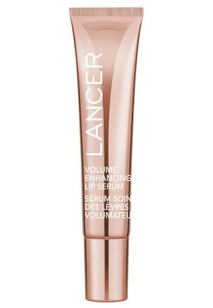 Rosa-goldene Röhrenverpackung für ein Lippenserum mit weißem Text. Sie verfügt über eine glatte Textur und einen runden Deckel. Die Etiketten sind in Englisch und Französisch.