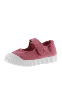 Zapato infantil tipo Mary Jane de lona rosa con suela de goma blanca y tira ajustable de velcro.