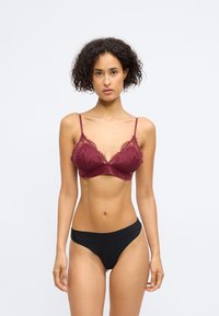 Bralette de encaje burdeos con tirantes ajustables, que presenta un borde festoneado y una banda inferior suave, acompañado de bragas negras sin costuras.
