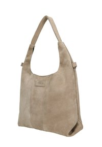 Sac à main en suédine beige avec une large bandoulière, des coutures visibles et une petite étiquette rectangulaire sur le panneau avant.