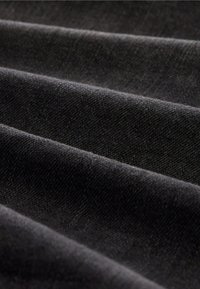 Tela negra que muestra múltiples pliegues, con una textura suave y un sutil patrón de tejido, que indica un material denso y duradero.