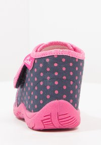 Navy fabric boot with pink polka dots, pink strap with hook-and-loop closure, textured rubber sole, and padded collar for comfort.
