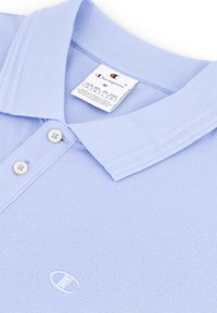 Jasnoniebieska koszulka polo z teksturowanej tkaniny, z kołnierzykiem do złożenia, dwoma guzikami i haftowanym logo z przodu.