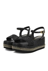 Sandali wedge neri con cinturini superiori intrecciati, fibbia regolabile alla caviglia e cuciture chiare a contrasto lungo il bordo spesso della piattaforma.