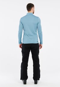 Šviesiai mėlynas ilgo rankovės marškinis su apykakle, derinamas su juodomis kelnėmis, turinčiomis šoninius užtrauktukus ir prisitaikančią apdarą.