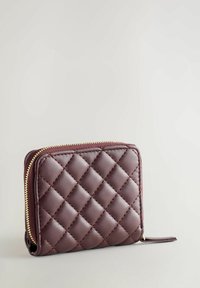 Portefeuille en cuir maroon matelassé avec une fermeture éclair dorée, présentant un design carré et une surface texturée avec des motifs en diamant.