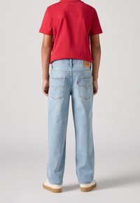 Ljusblå denim jeans med rak passform, som har en beige läderlapp vid bak i midjan och två bakfickor med subtila sömdetaljer.