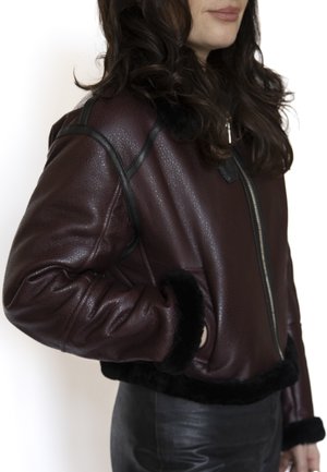 Bordeauxfarbenes Lederjacke mit Reißverschluss, schwarzem Fellbesatz am Kragen und den Bündchen, mit strukturiertem Material und einem kurzen Schnitt.