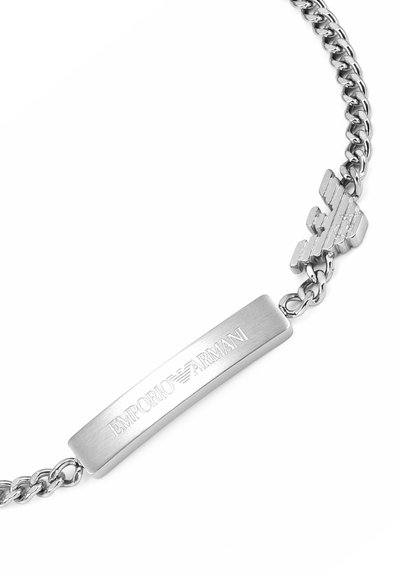 Bracelet en métal argenté avec une plaque rectangulaire plate gravée de "EMPORIO ARMANI" et un détail logo sur un côté ; design à chaîne maillon.