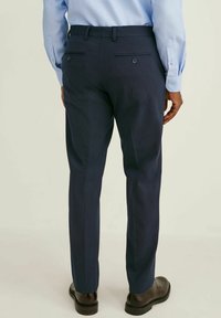 Marina anpassade byxor med ett subtilt ränder mönster, två bakfickor och bältesöglor. Bärs med blanka bruna finskor.