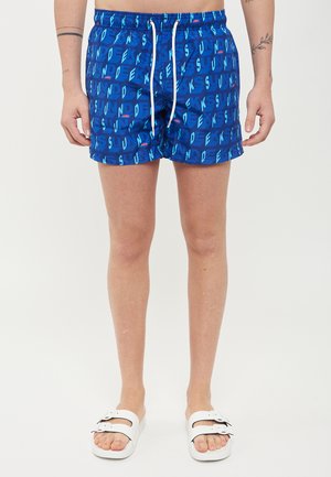 Costumi da bagno blu con un motivo di testo ripetitivo in tonalità di blu e teal, dotati di un elastico in vita e di un tessuto traspirante.