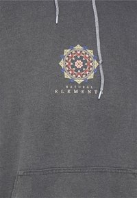 Tmavě šedá mikina s kapucí na stažení. Obsahuje barevný mandala design a text "PŘÍRODNÍ ELEMENTY" pod ním. Měkká textura.