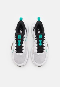 White and black athletic shoes with turquoise accents, textured mesh upper, and flat laces. Features a pull tab on the heel and logo details.