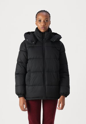 Veste doudoune noire avec col haut, fermeture éclair et capuche amovible. Dotée de poignets élastiques et de boutons sur les côtés, offrant un look matelassé et texturé.