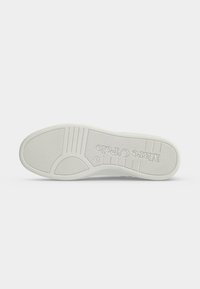 Semelle d'une chaussure blanche avec des rainures antidérapantes et le logo "Marco Tozzi" embossé en dessous.