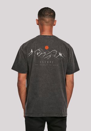 Schwarzes Baumwoll-T-Shirt mit einem Berg-Graphic und einem roten Sonnenprint auf dem Rücken. Kurzärmlig und mit lockerer Passform sowie sichtbaren Nähdetails.