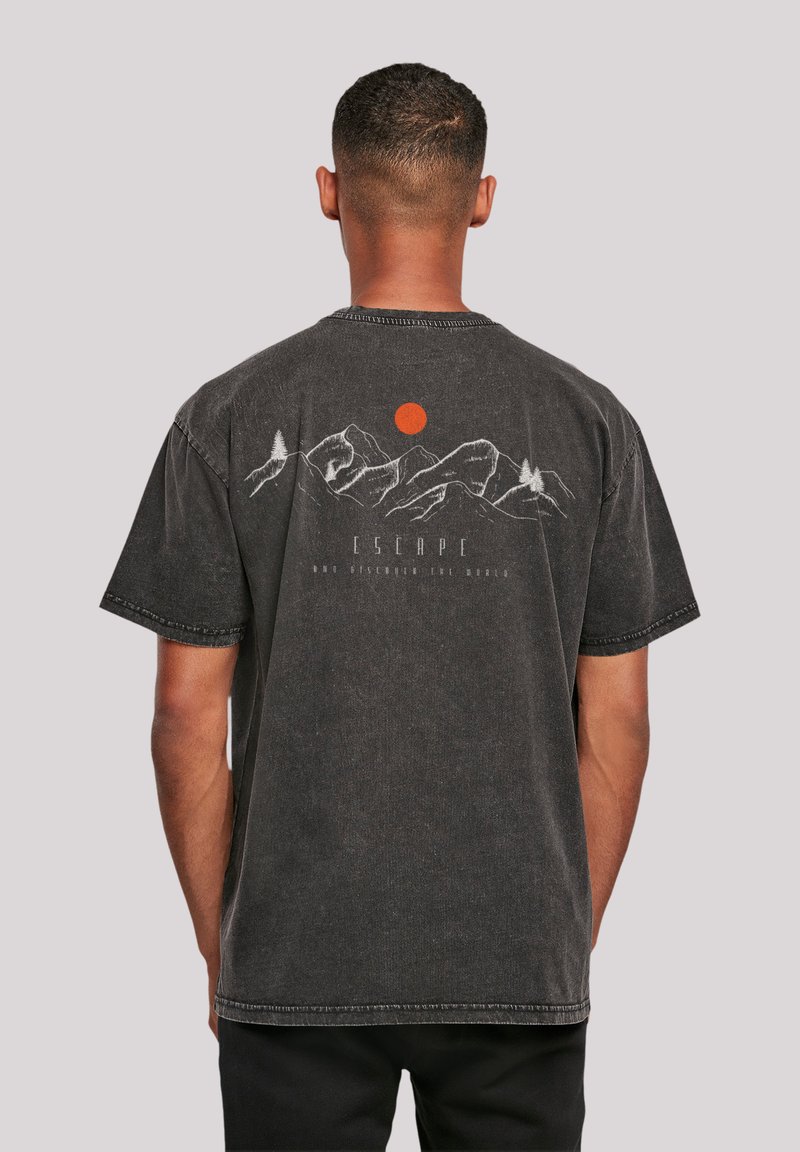Zwarte katoenen T-shirt met een bergafbeelding en een rode zonprint op de rug. Korte mouwen en een ontspannen pasvorm met zichtbare stikdetails.